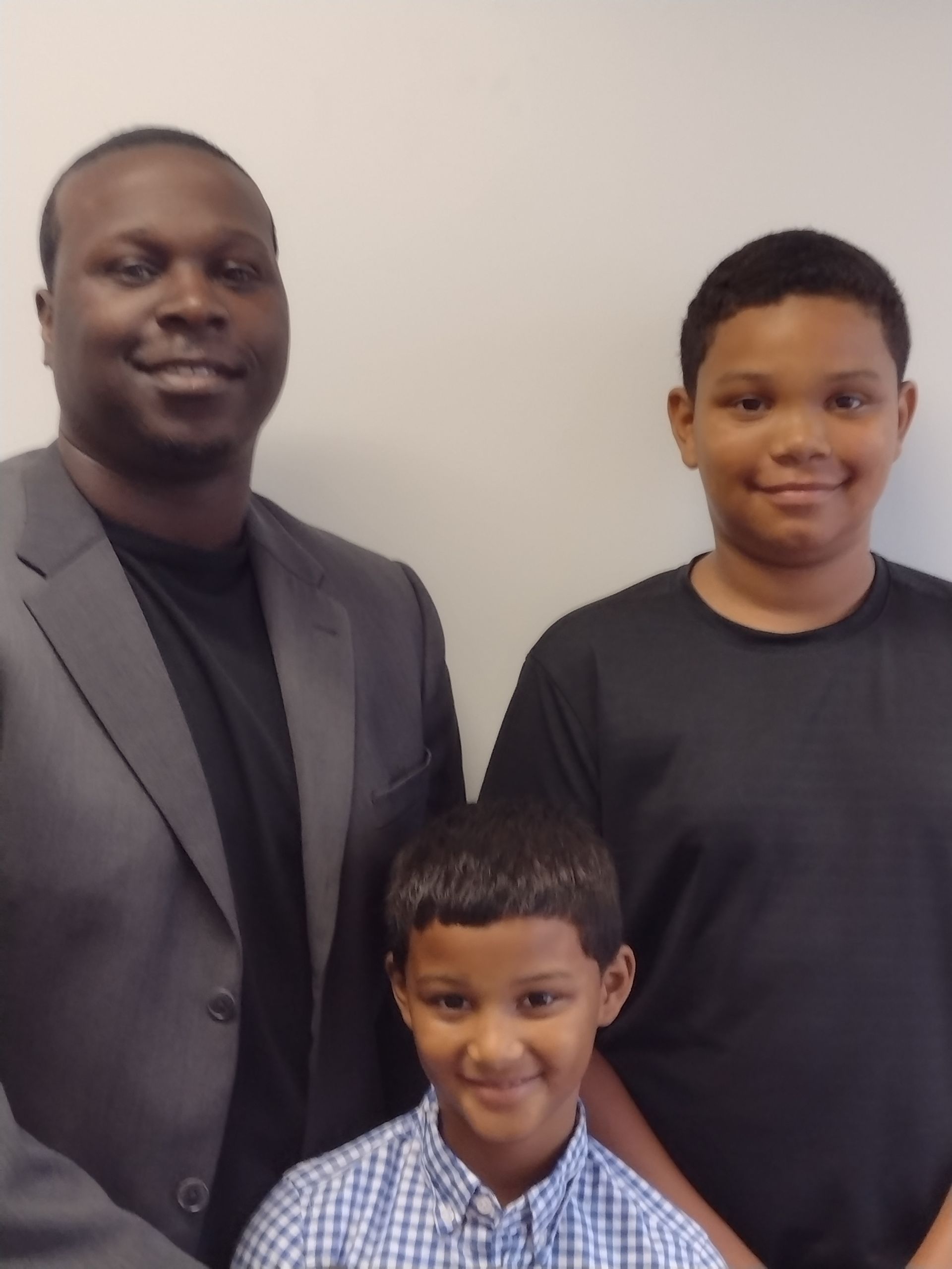 A man in a suit stands next to two young boys