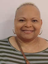 A woman wearing a striped shirt and earrings is smiling for the camera.