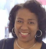 A woman wearing a necklace and earrings is smiling for the camera.
