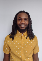 A man with dreadlocks is wearing a yellow shirt with white polka dots.