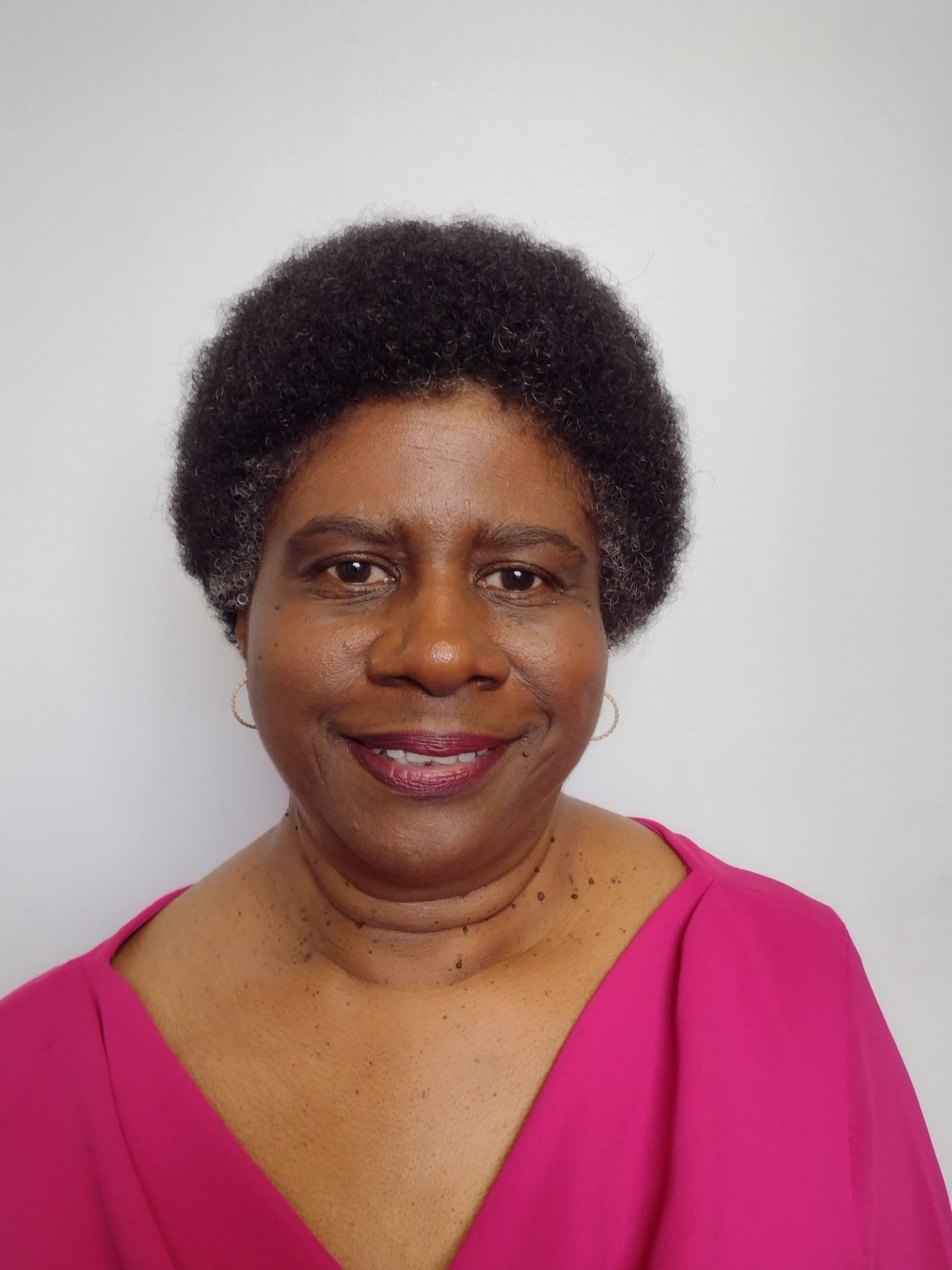A woman in a pink shirt is smiling for the camera