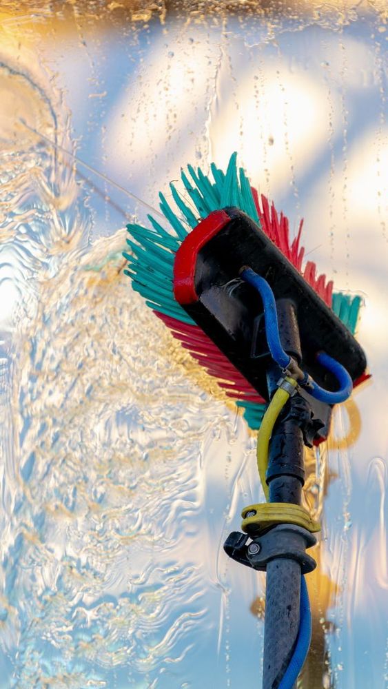A brush is being used to clean a window with water coming out of it.