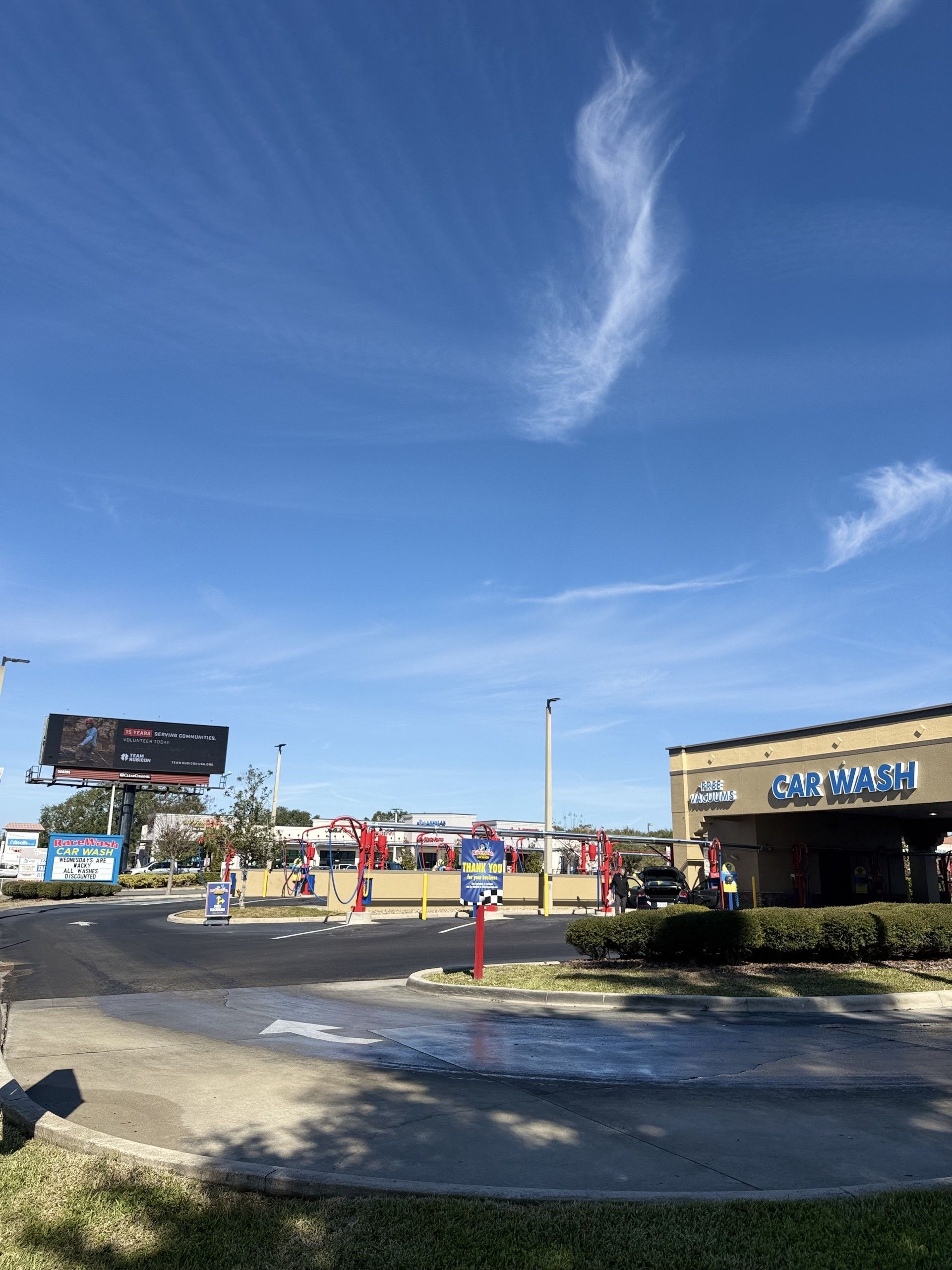 Car wash station with supplies: window cleaner, interior cleaner, and wiper fluid. Red and blue with smiling tire logo.
