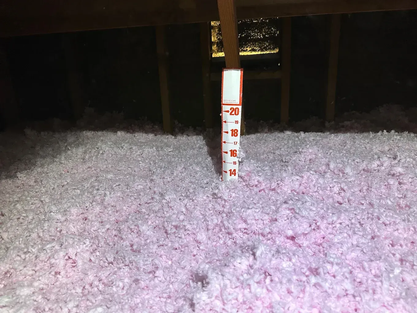 There is a measuring stick in the middle of a pile of insulation.