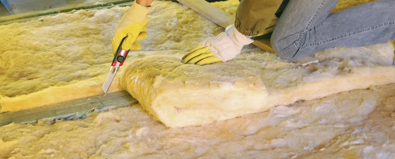 A person is cutting a piece of insulation with a saw.
