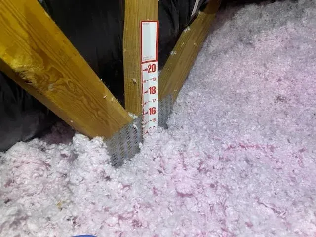 A ruler is sitting on top of a pile of pink insulation.
