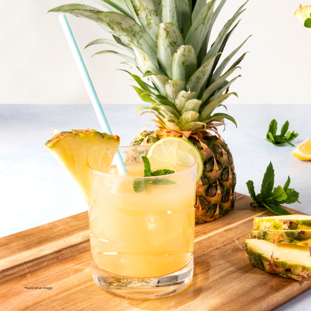 A glass of pineapple juice with a pineapple in the background