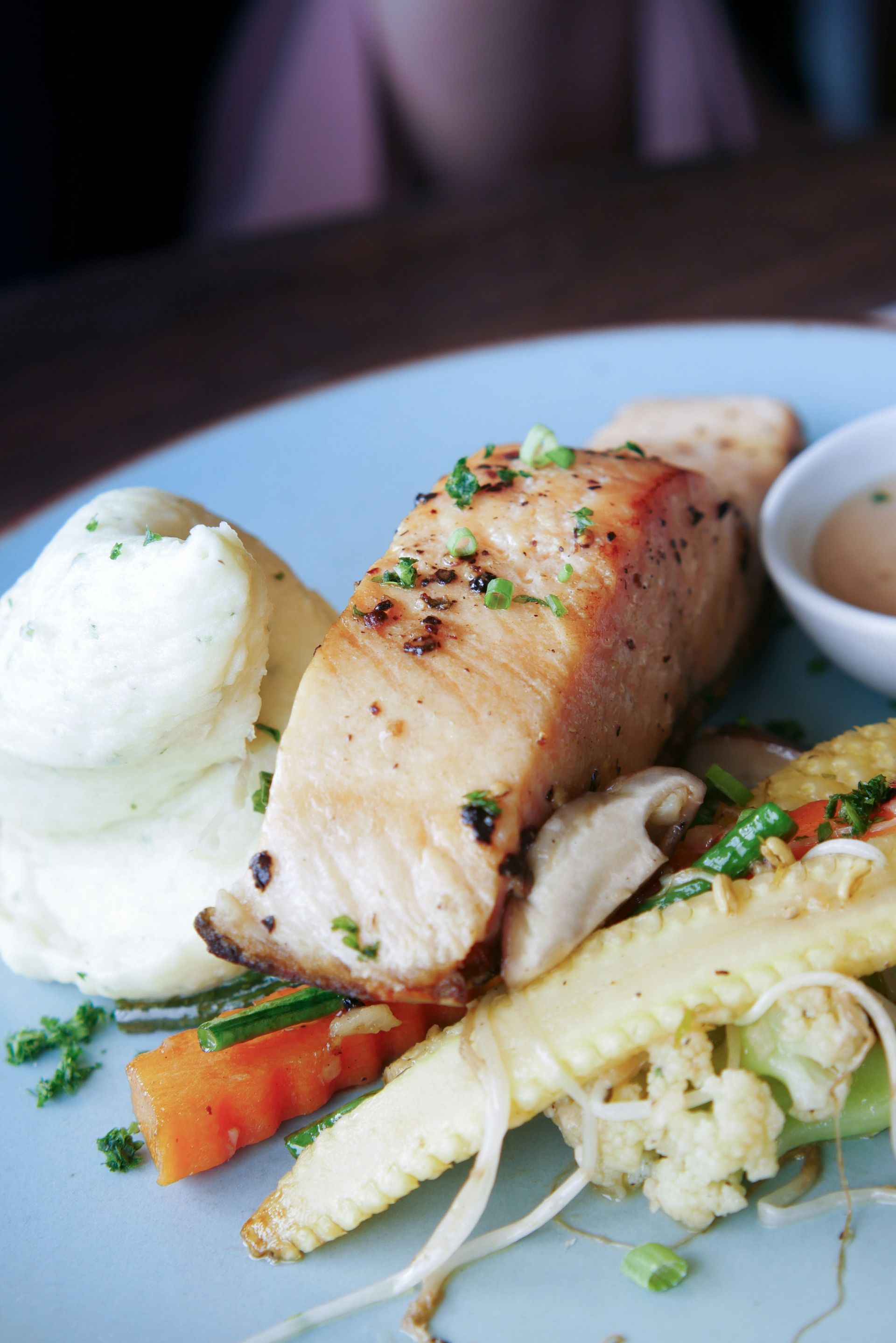 A close up of a plate of food with meat and vegetables on a table.