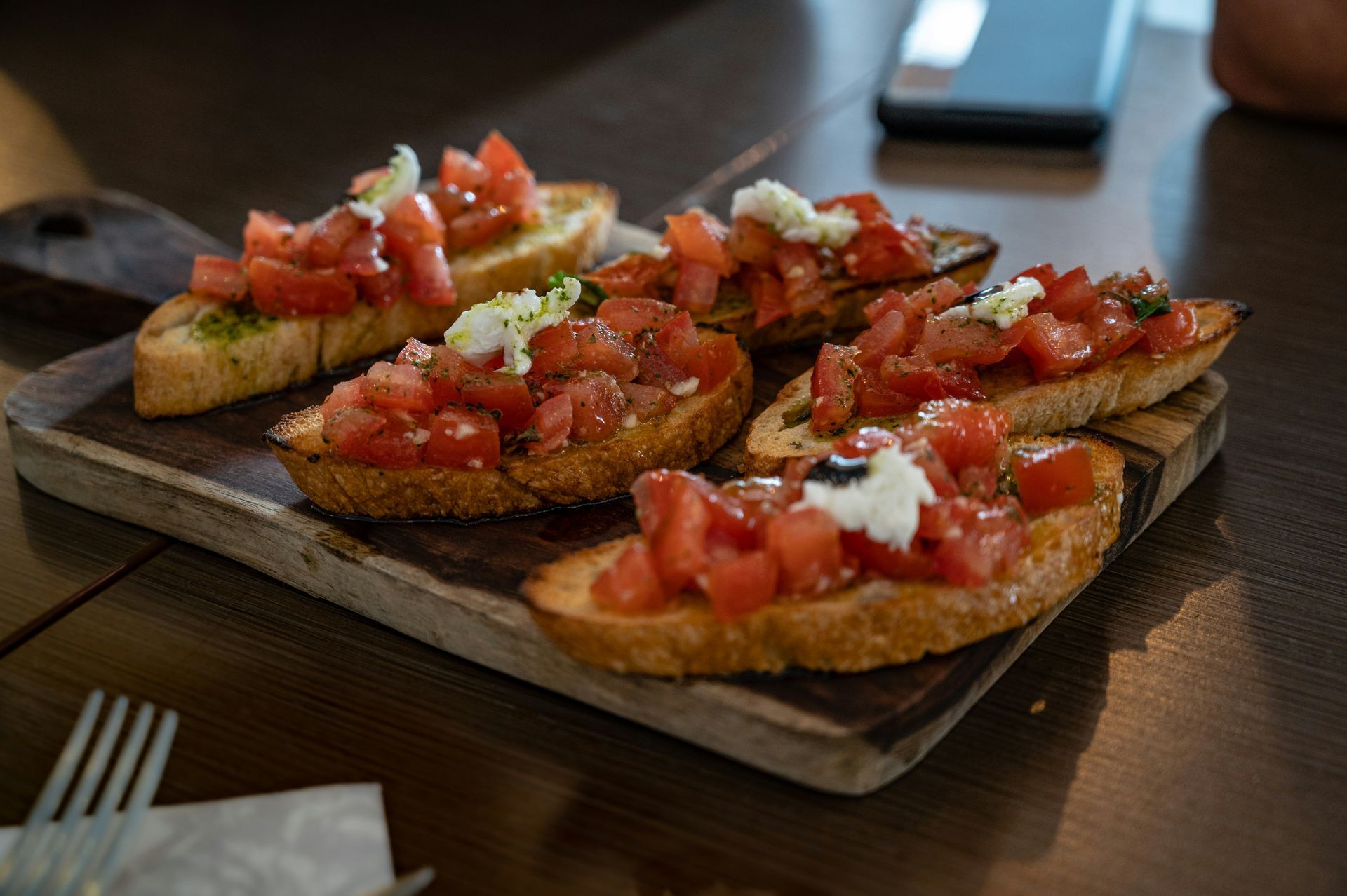 A wooden cutting board topped with slices of bread and tomatoes.