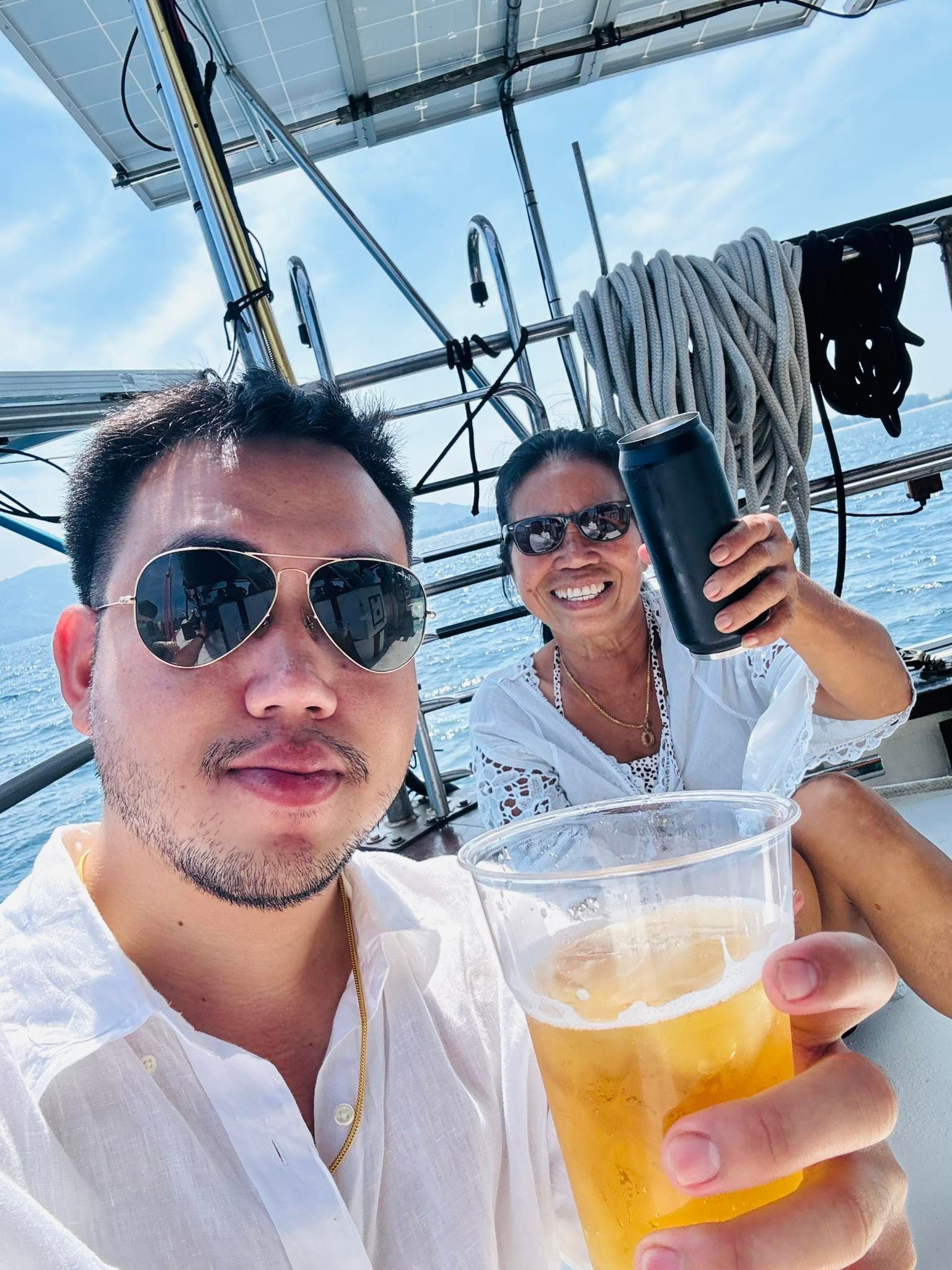 A man and a woman are toasting with beer on a boat.