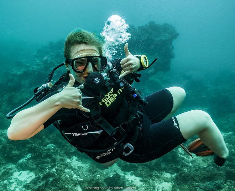 A scuba diver is giving a thumbs up in the ocean