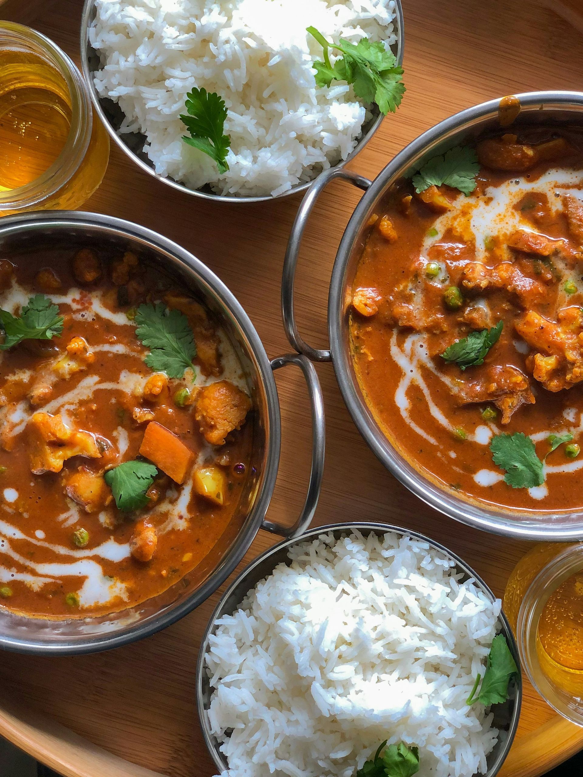 Three bowls of curry and rice are on a wooden table.