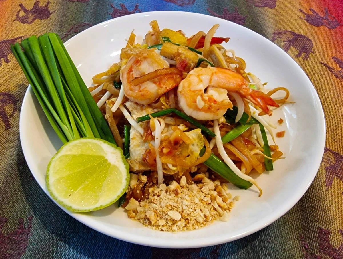 A white plate topped with shrimp noodles and vegetables