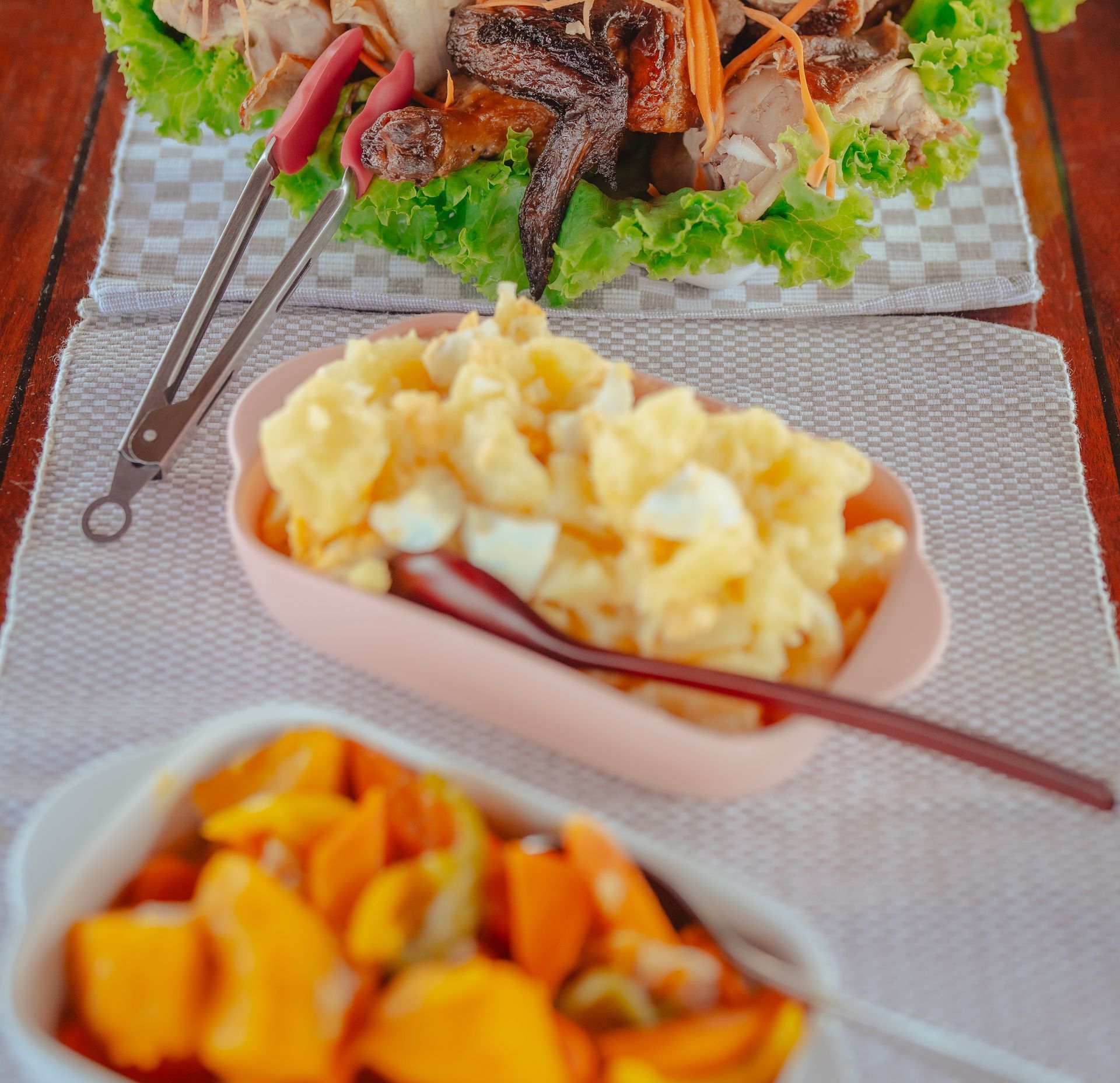 A plate of food with a spoon and tongs on a table