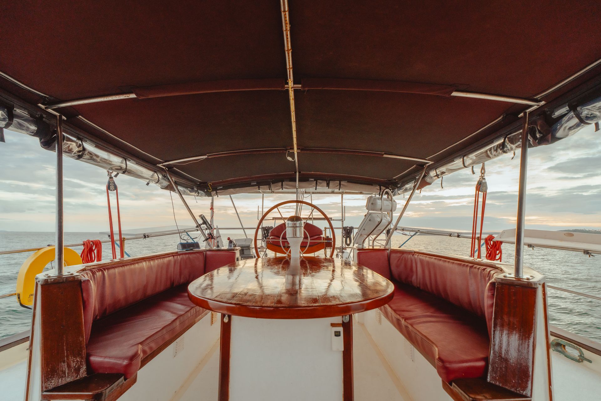 The inside of a boat with a table and a steering wheel.