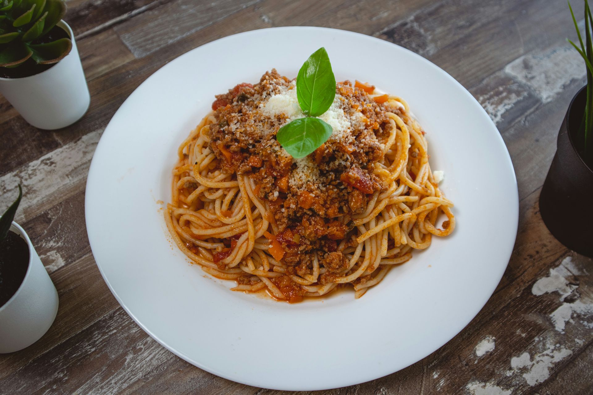 A white plate topped with spaghetti and meat sauce on a wooden table.