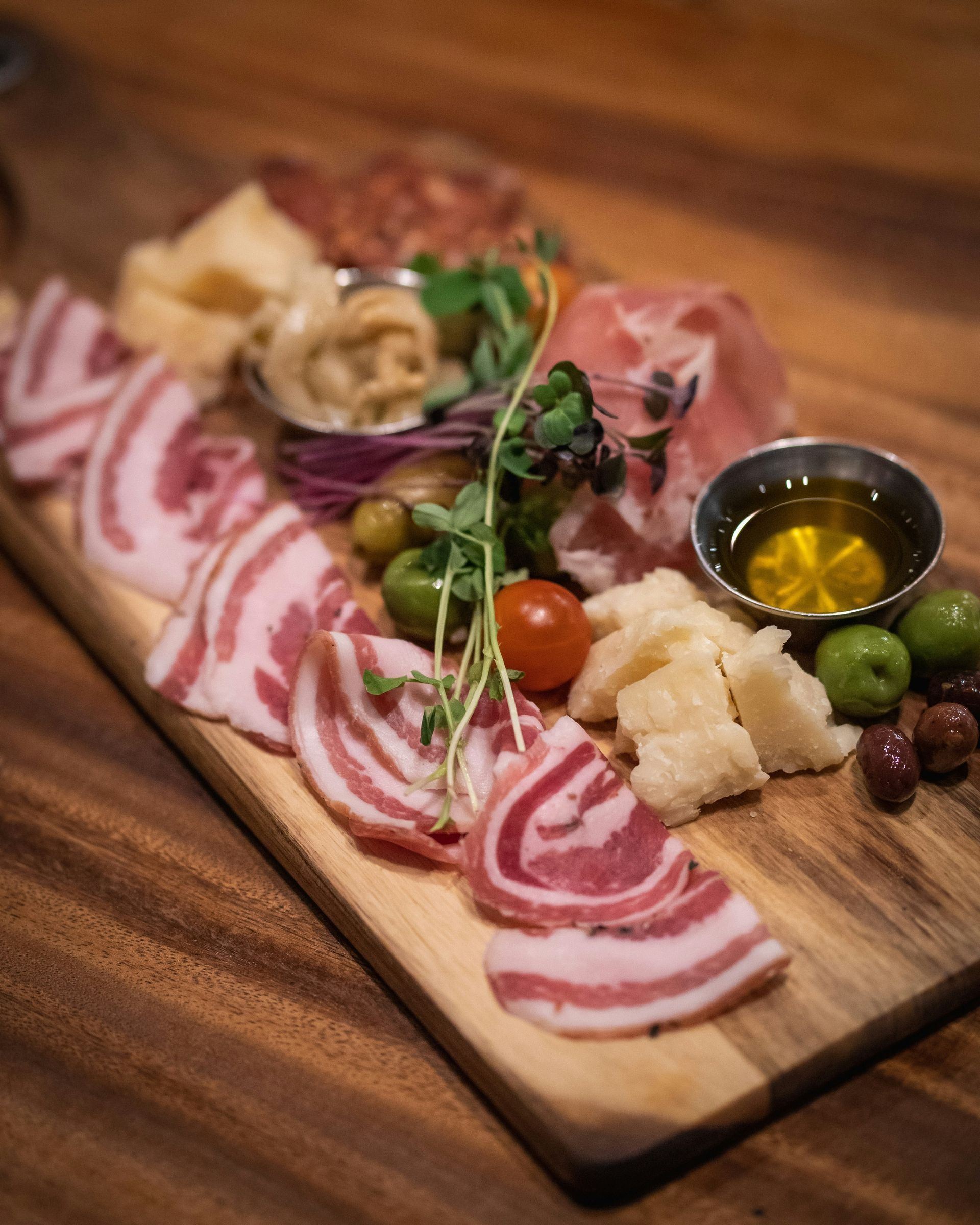 A wooden cutting board filled with meat and vegetables on a table.