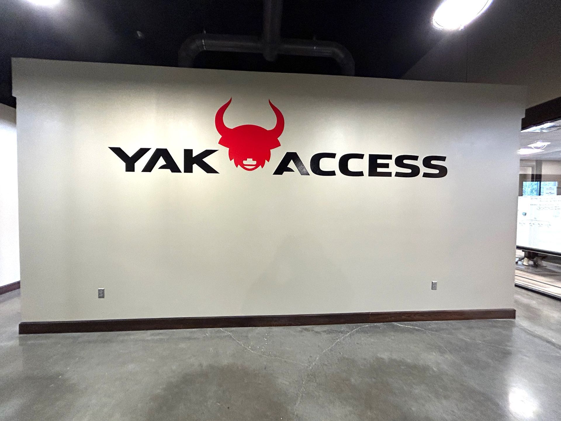 The Yak Access logo with a red stylized bull head icon and black text on a neutral office wall.