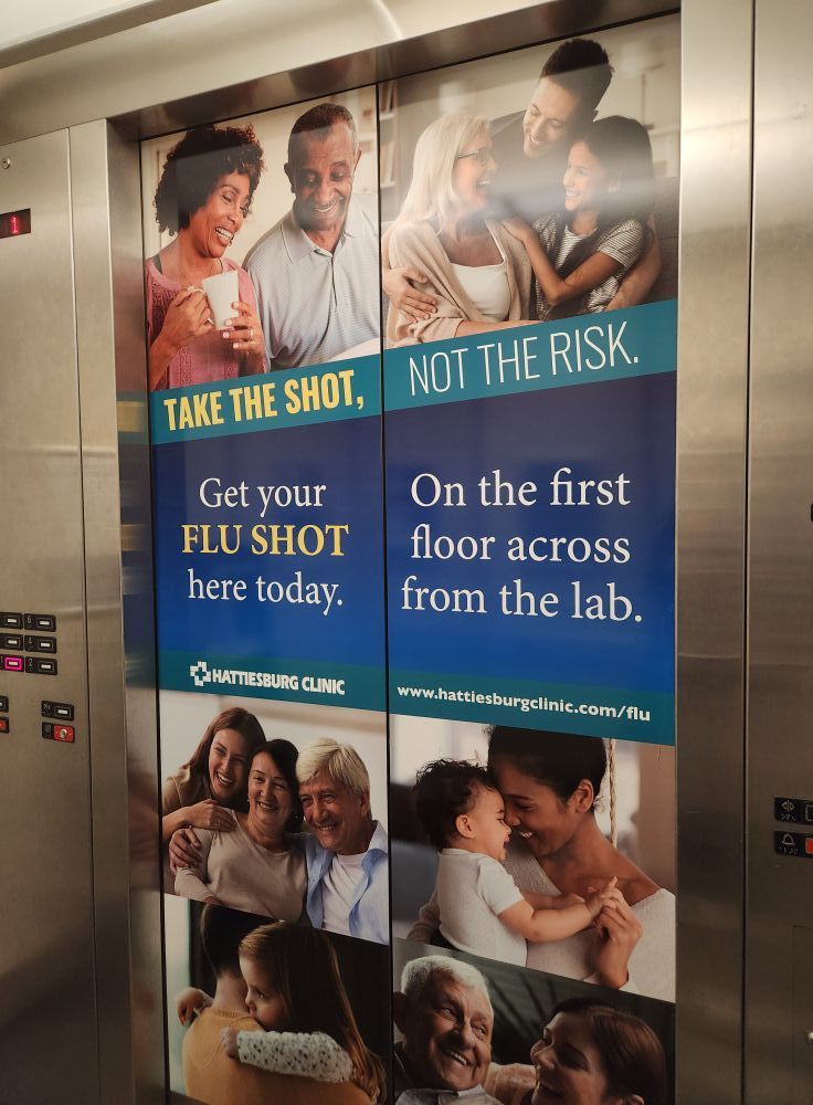 An elevator door features a flu shot advertisement with photos of people and the text 