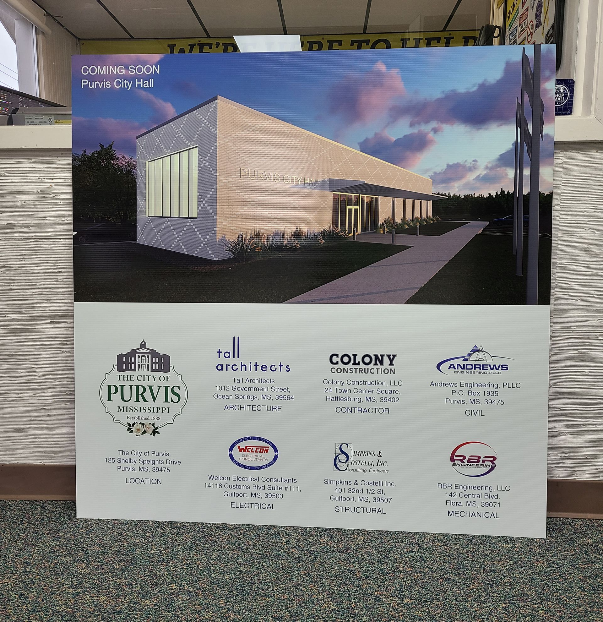 A display sign showing a rendering of a new building project, including logos for the architects and construction firms.