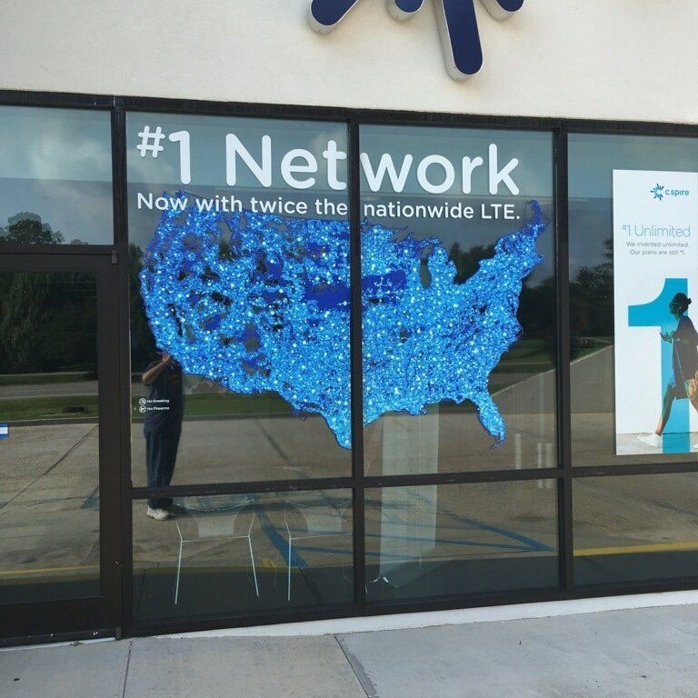 Storefront window with a map of the United States covered in blue network-coverage dots under the text 
