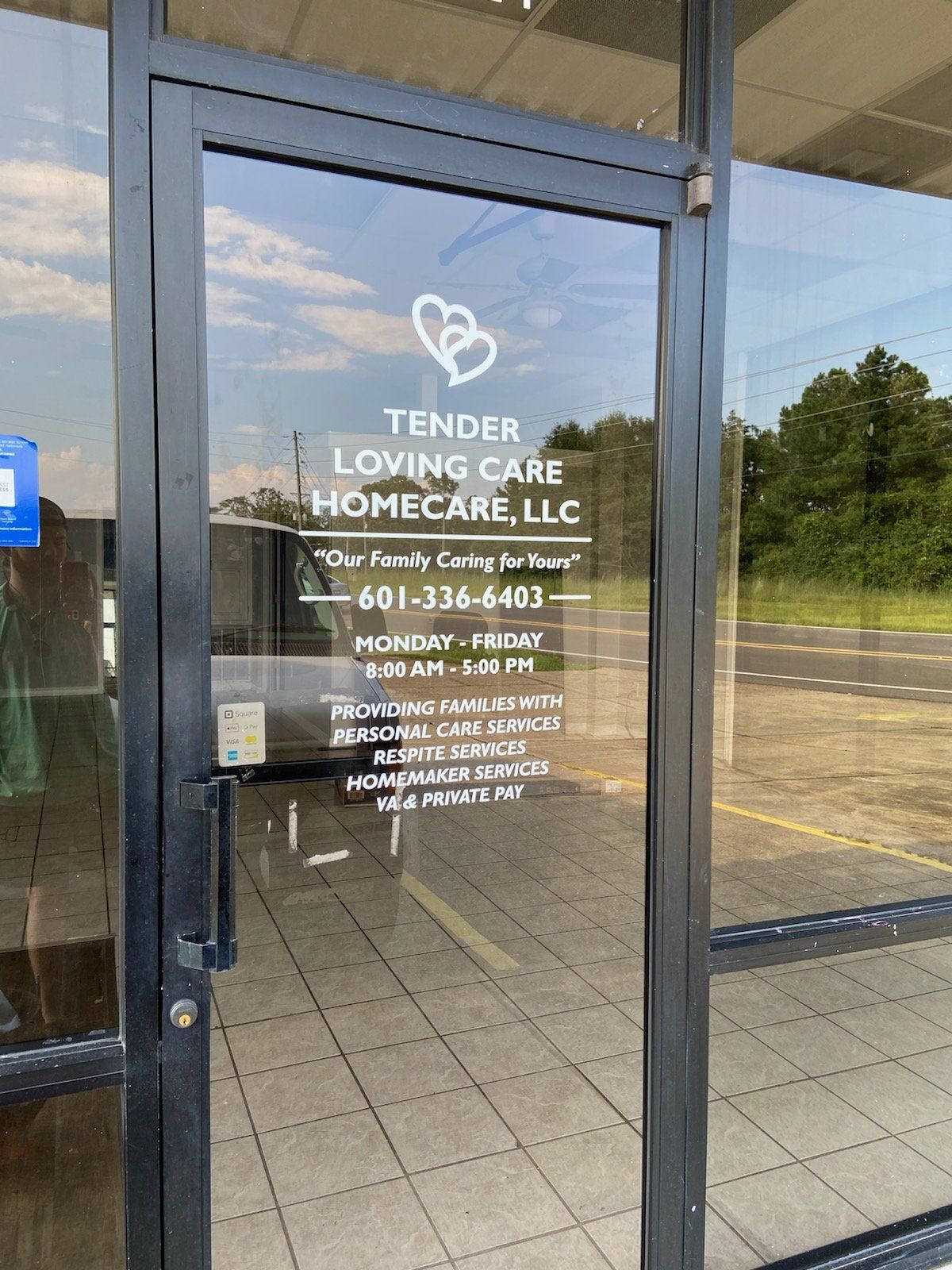 Glass front door of Tender Loving Care Homecare, LLC with hours, phone number, and services printed in white.