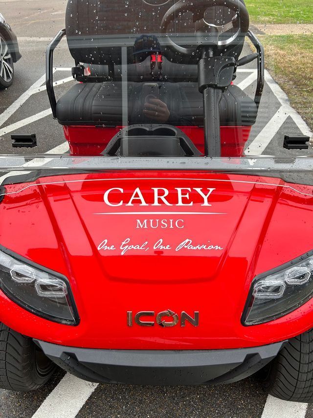 A bright red ICON golf cart parked in a parking space, featuring the text 