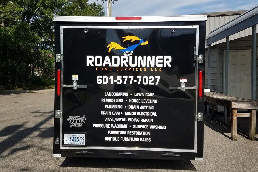 Back of a Roadrunner Home Services LLC trailer featuring a contact number and a list of various home repair services.