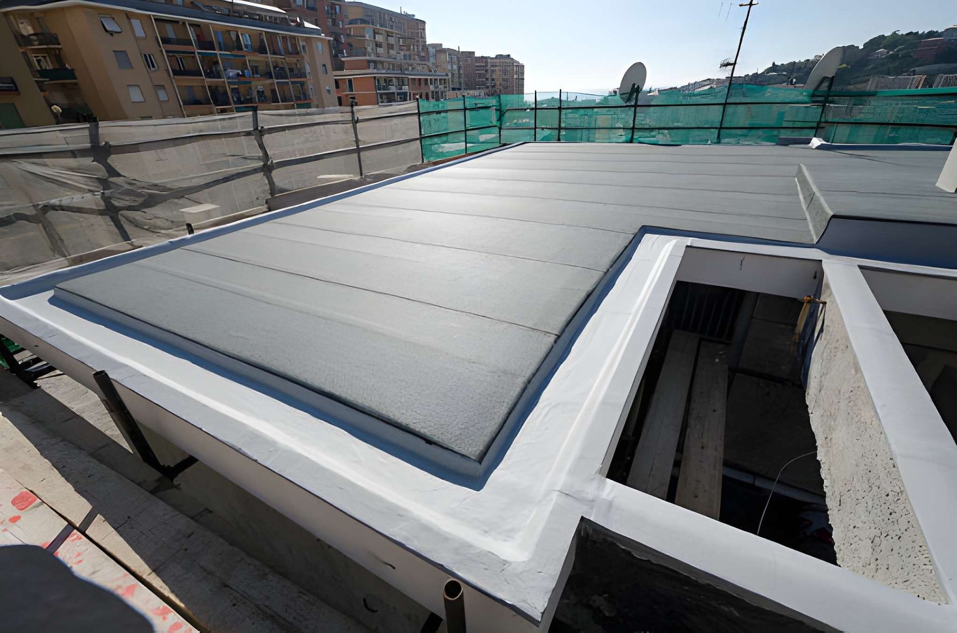 Flat roof with gray and white waterproof membrane, construction site.