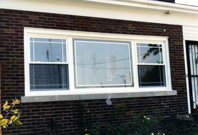 Sliding windows separated by one large window installed in brown home Tonawanda, NY