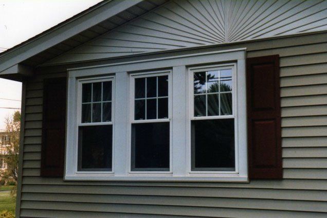 Vertical sliding windows with brown shutters Grand Island, NY