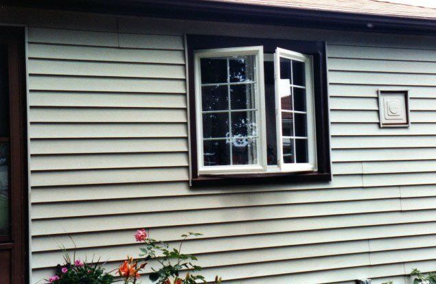 Open sliding windows set in a green vinyl-sided home Buffalo, NY