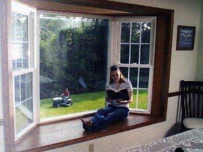large bay window with wood trim with a child sitting reading it in Amherst, NY