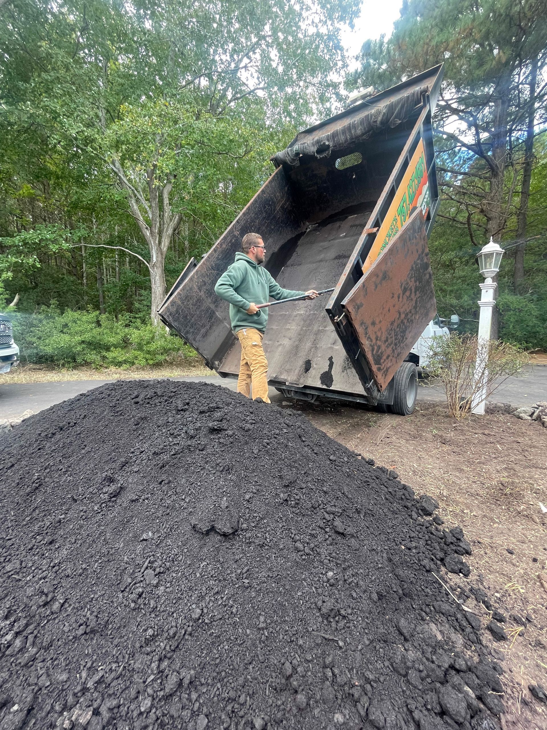 a man is standing next to a dump truck filled with dirt .