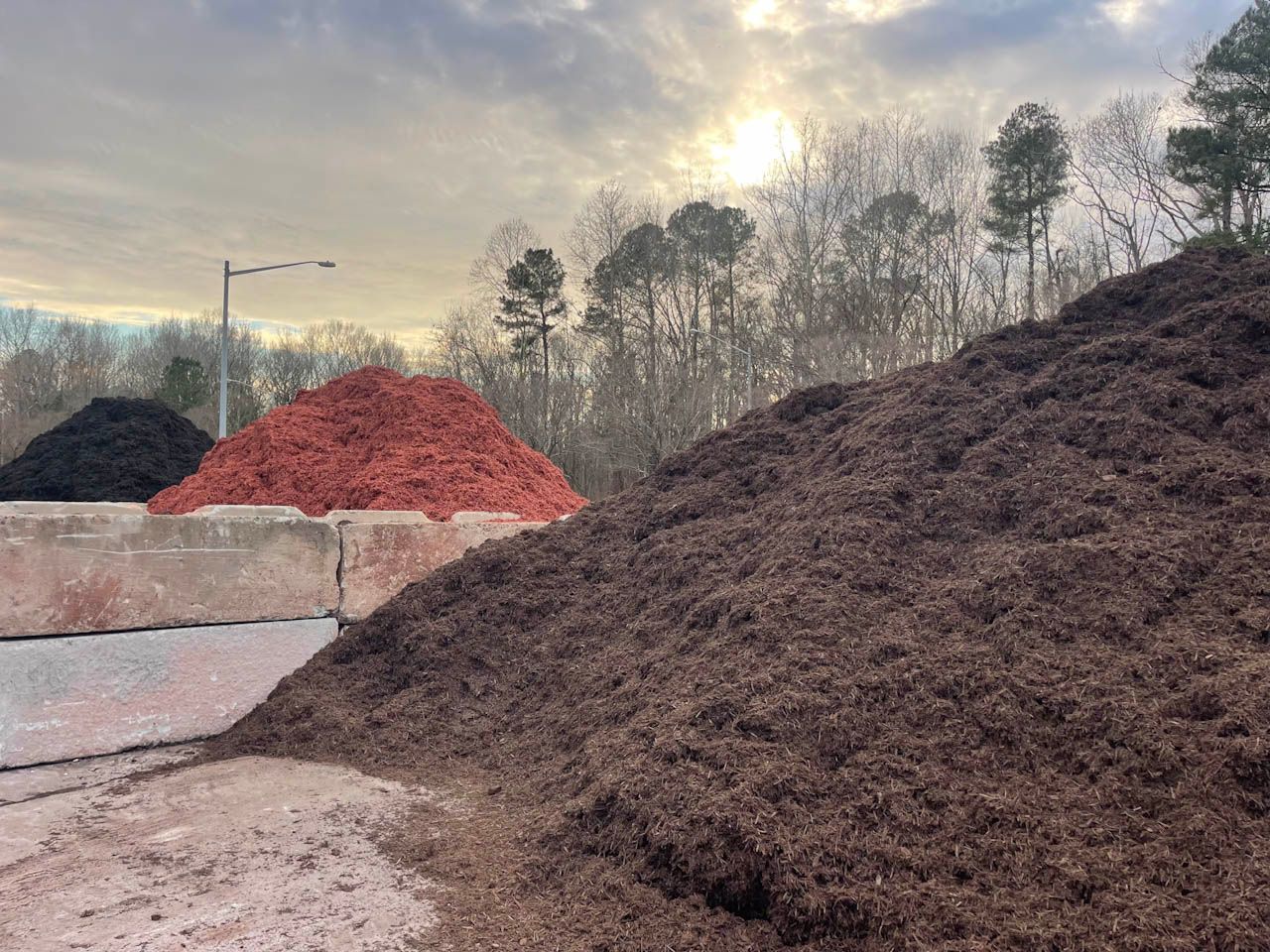 three piles of mulch are lined up in a parking lot
