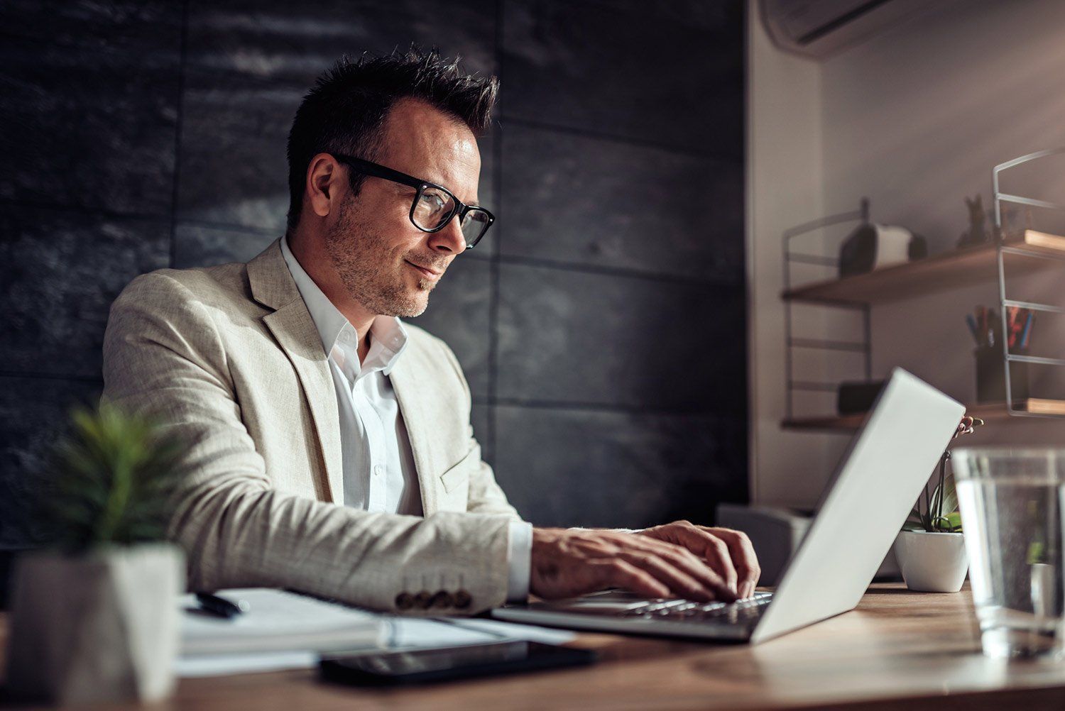 A man is sitting at a desk using a laptop computer.