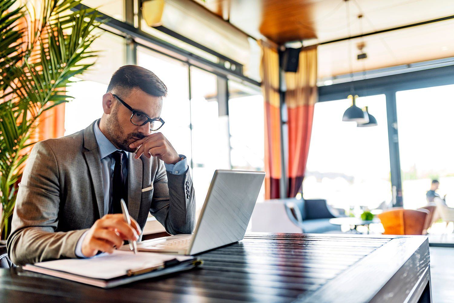 A man in a suit and tie is sitting at a table using a laptop computer.