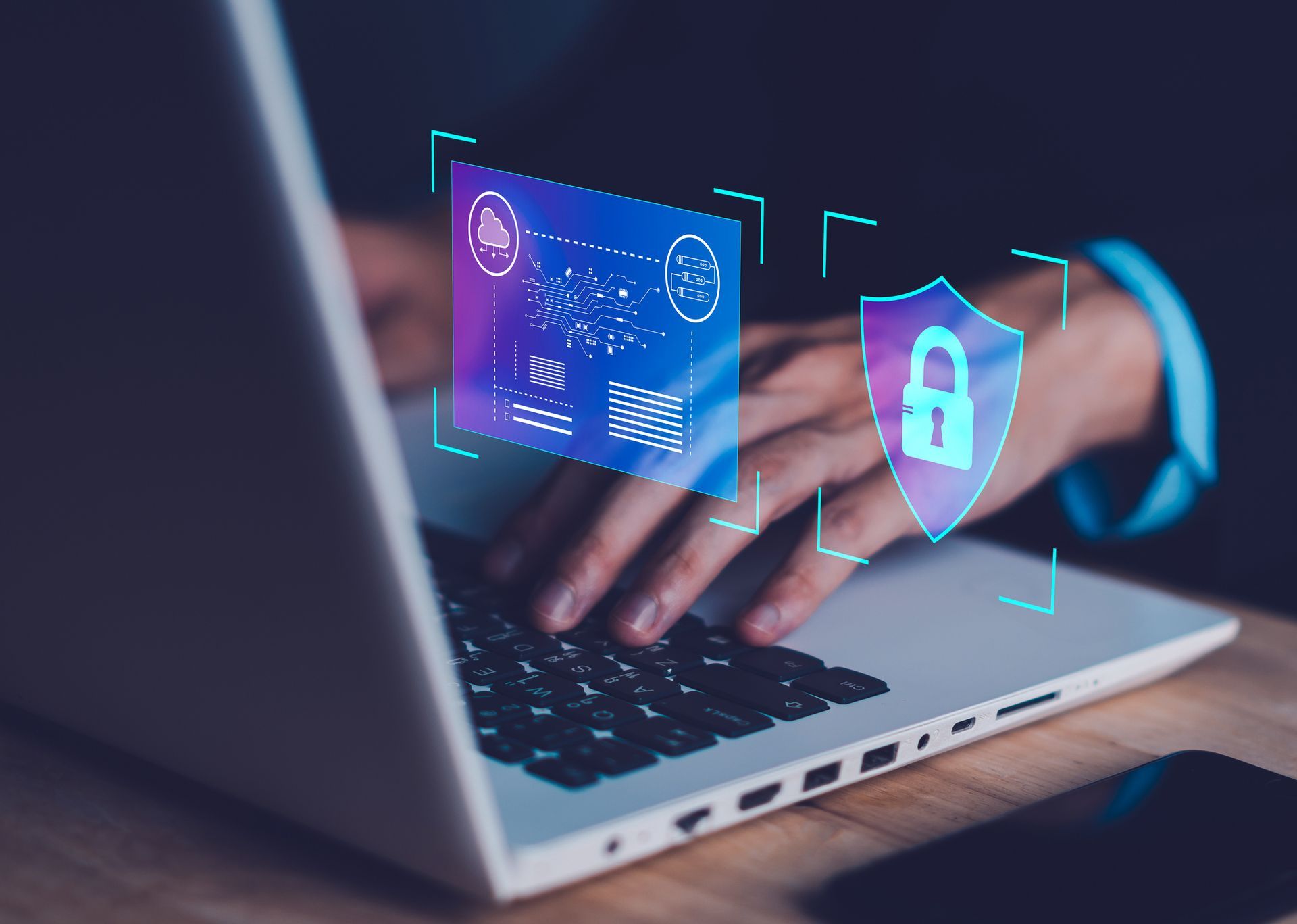 A person is typing on a laptop computer with a shield and a padlock on the screen.