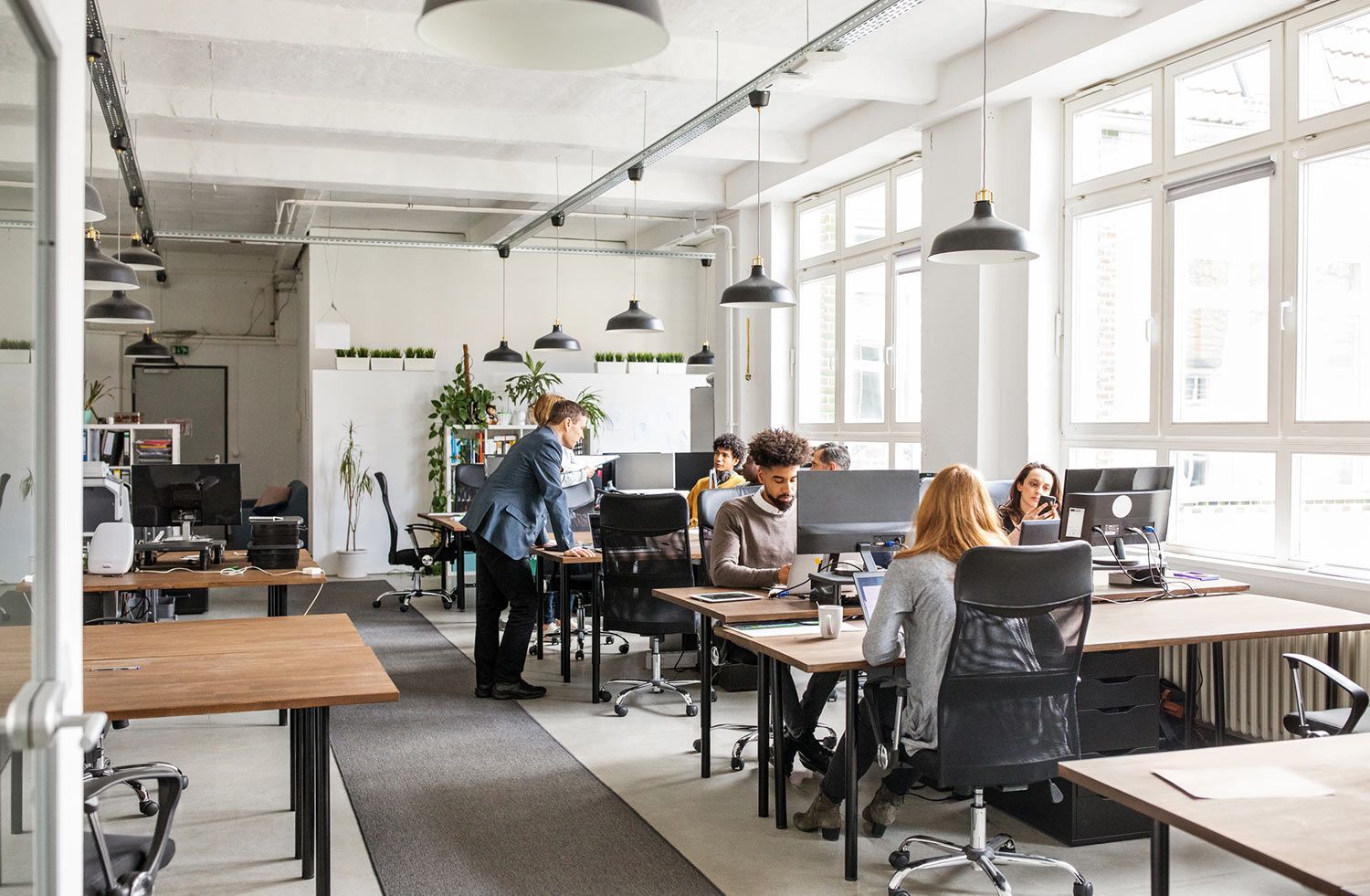 A group of people are sitting at desks in an office.