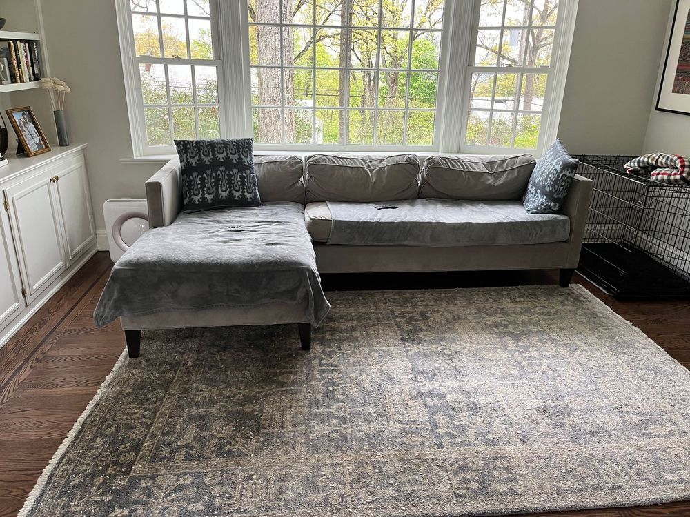 A living room with a sectional couch and a rug.