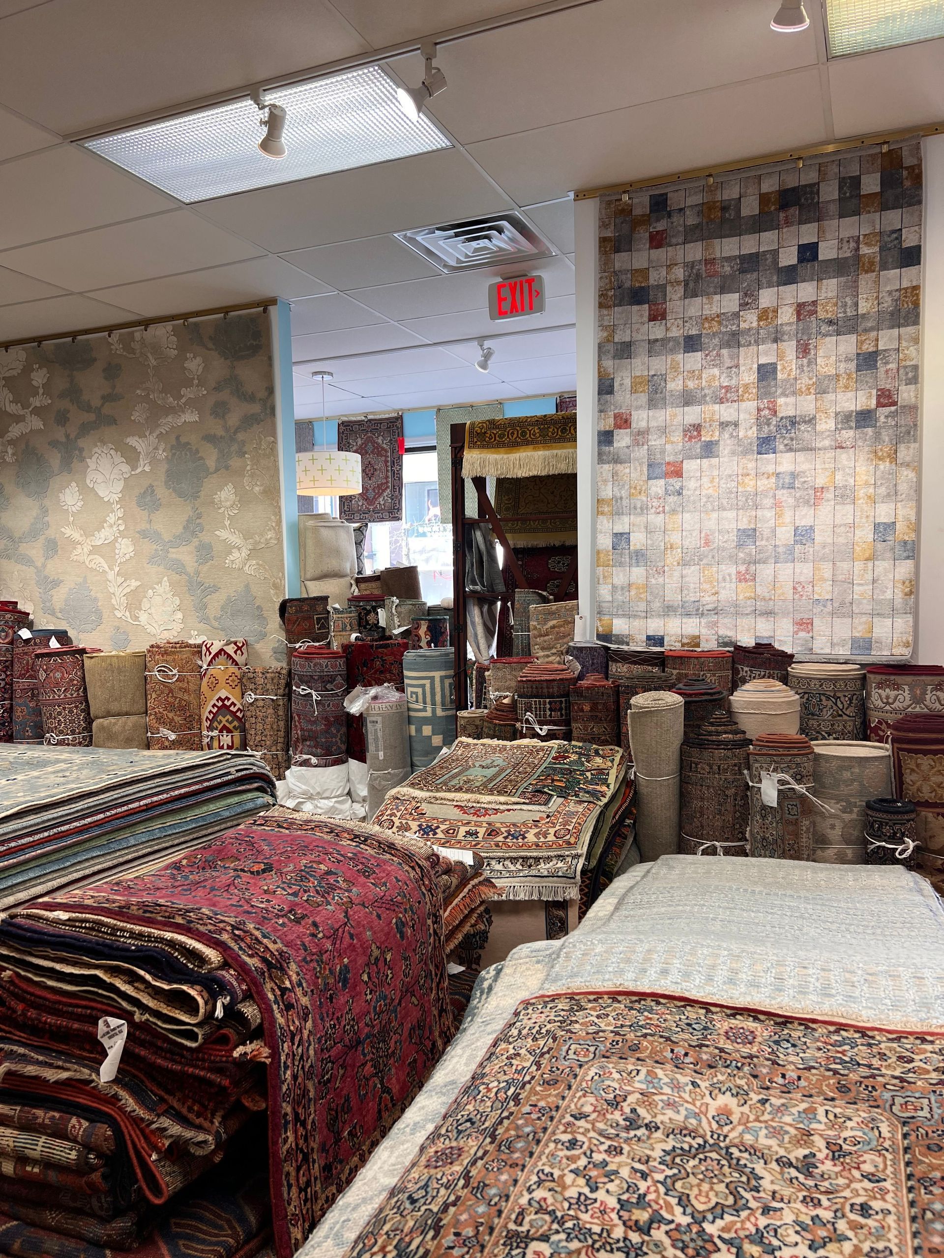 A room filled with lots of rugs and chairs in a store.