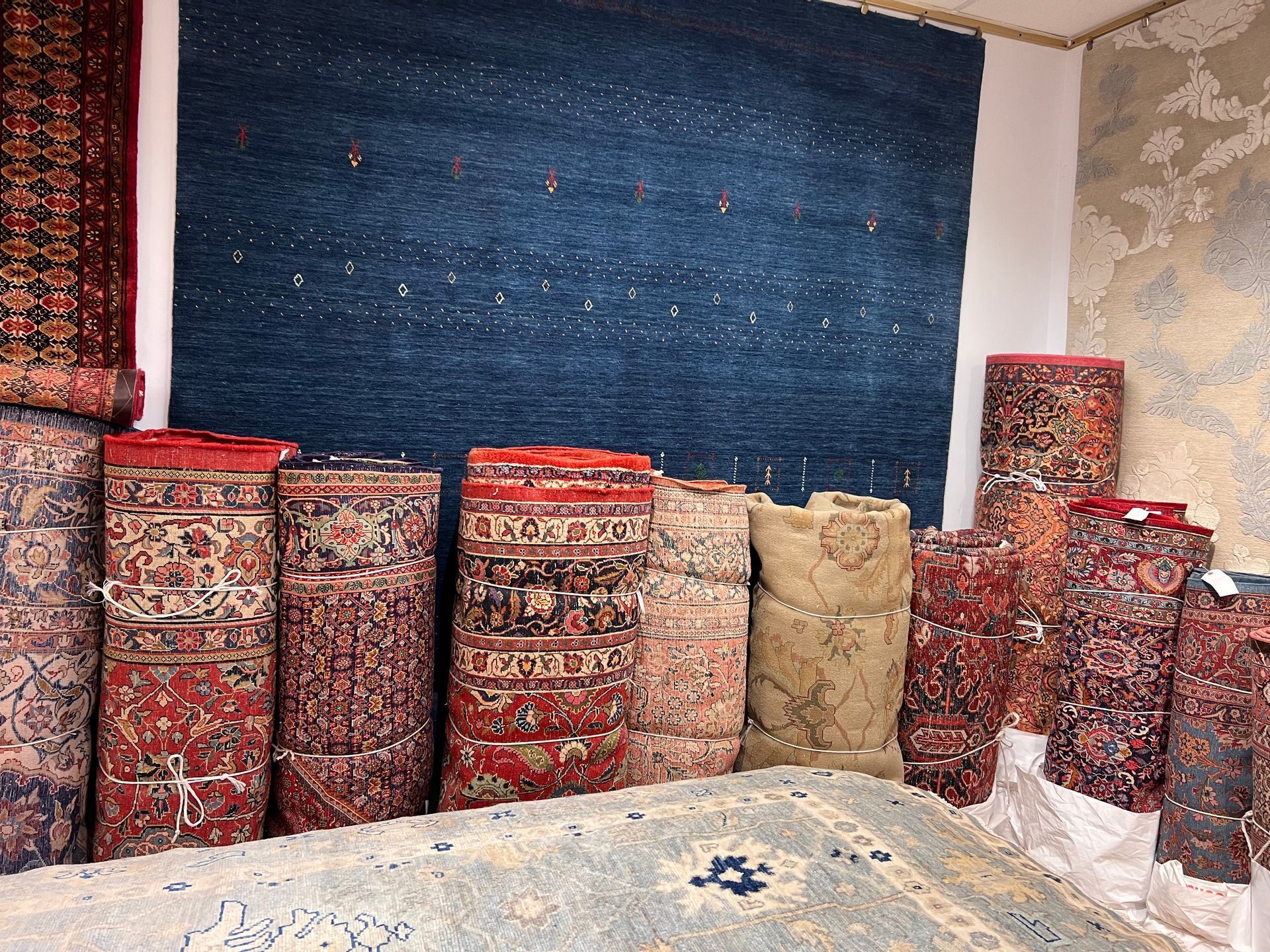 A bunch of rugs are stacked on top of each other in a room.