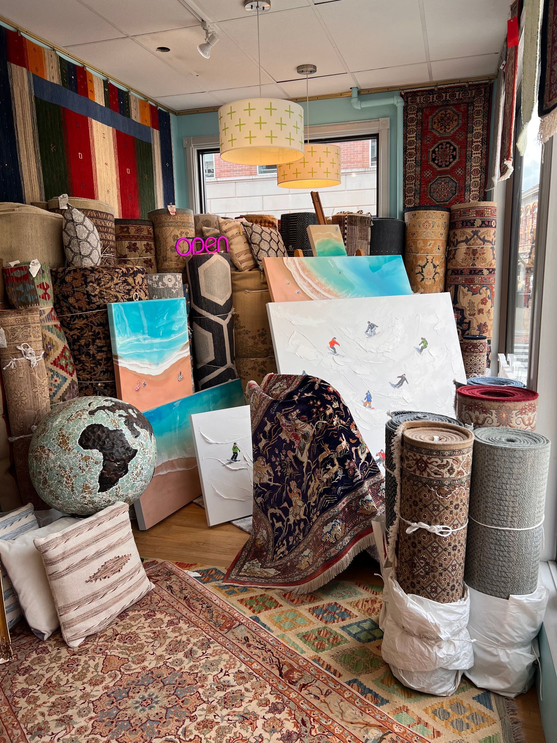 A room filled with lots of rugs and paintings.