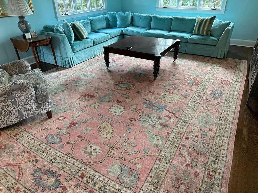 A living room with a pink rug , blue couches , and a coffee table.