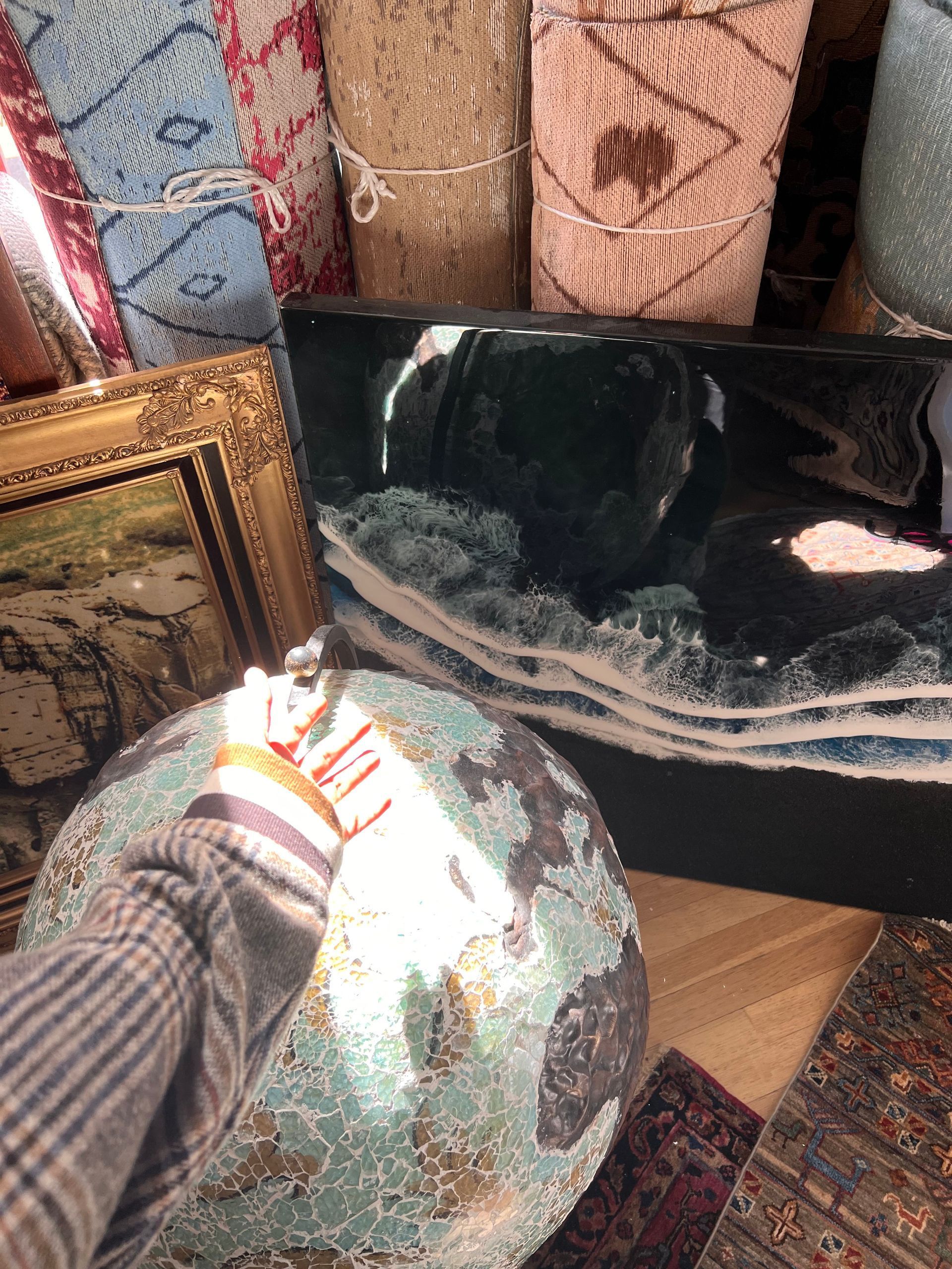 A person is holding a globe in front of a painting.