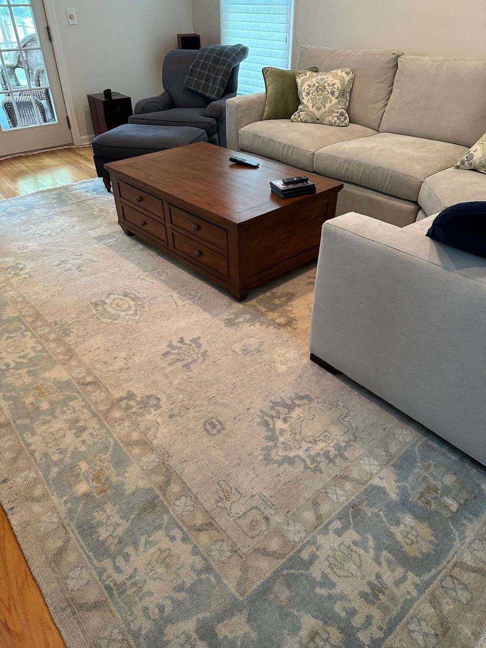 A living room with a couch , chair , coffee table and rug.