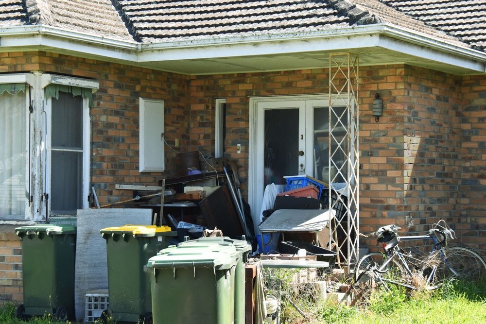 A brick house with trash cans and a bicycle parked in front of it.