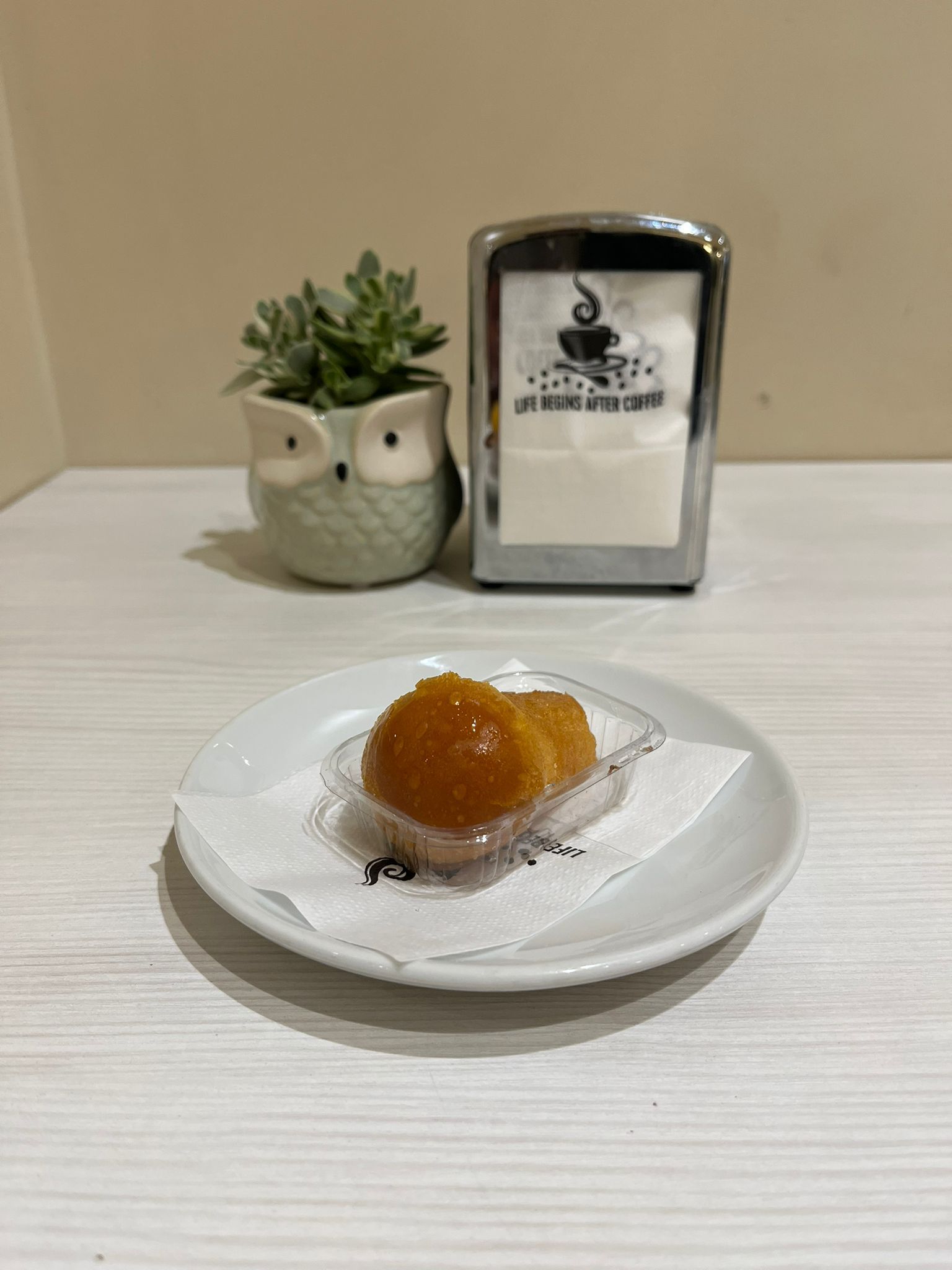 Pasta sfoglia su un piatto, accanto a un porta tovaglioli e a un vaso di succulente a forma di gufo.