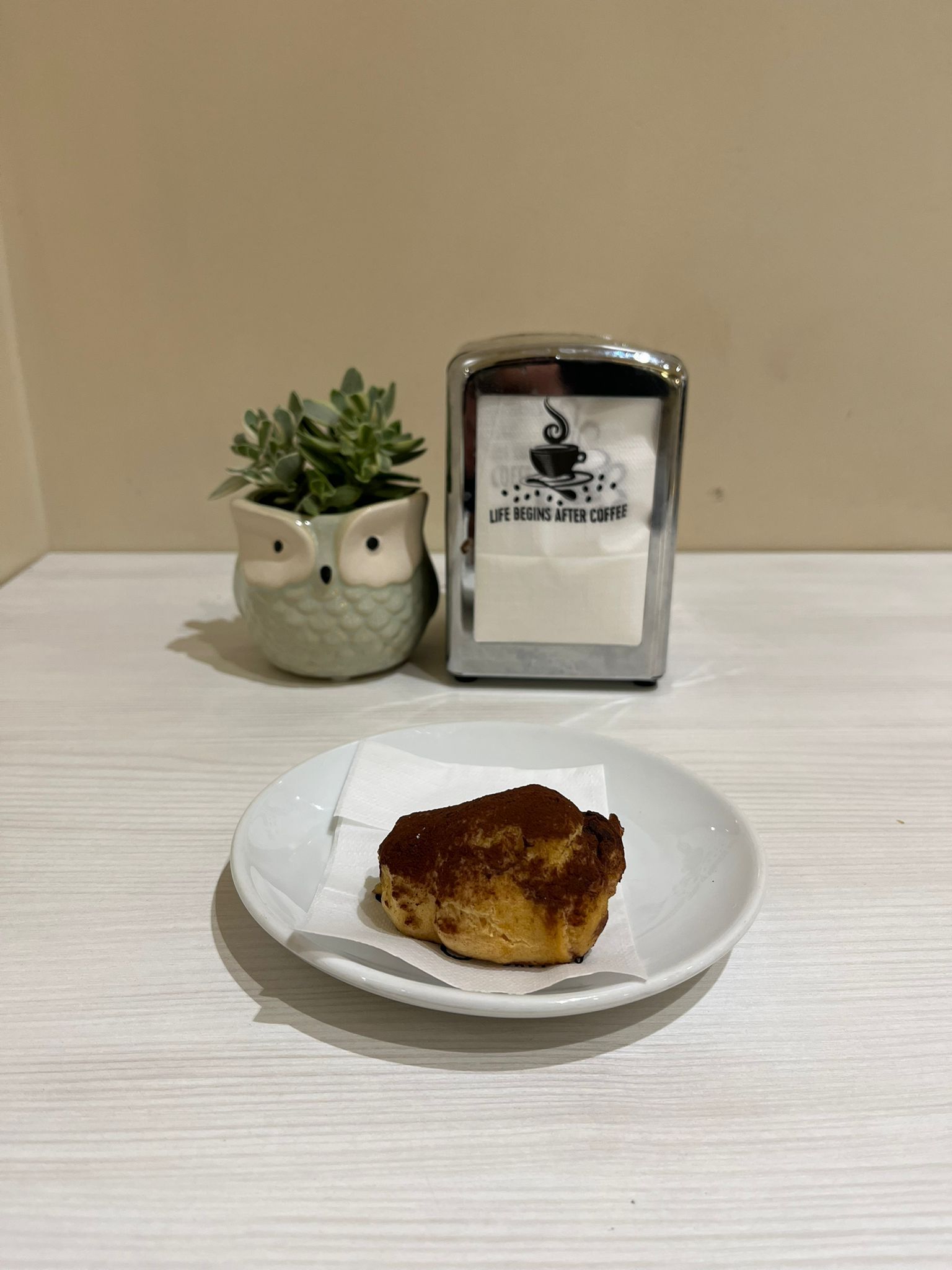 Un dolce su un piatto con un gufo come vaso e un porta tovaglioli su una superficie bianca.