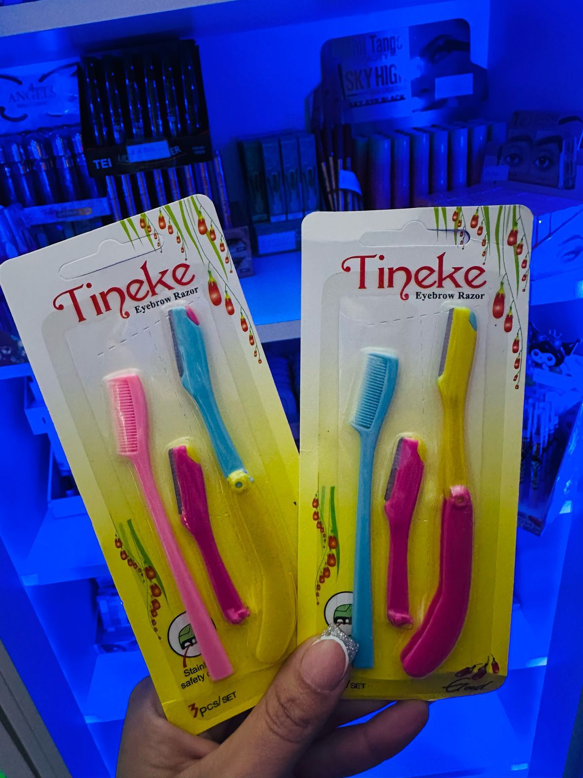 Una persona sostiene dos paquetes de maquinillas de afeitar para cejas Tineke.